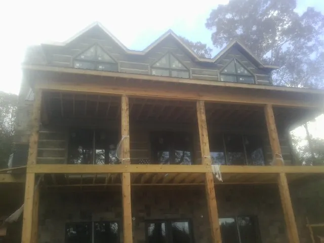 Dormers and porch framing on a large log home under construction — Roof Coating work by our crew in Admire