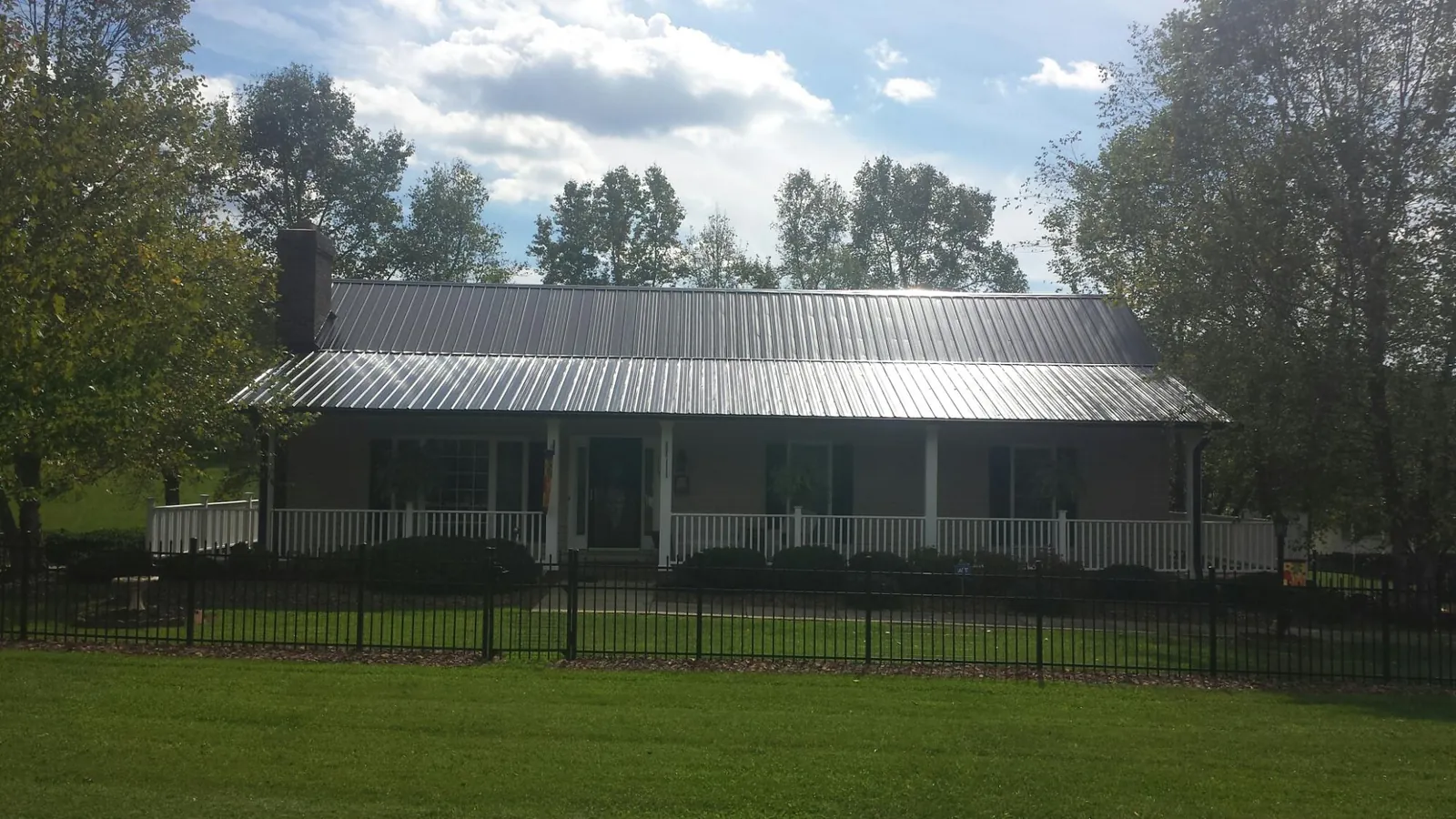 Gray metal roof on a brick ranch with a full width front porch — Gutter Guard Installation work by our crew in Admire