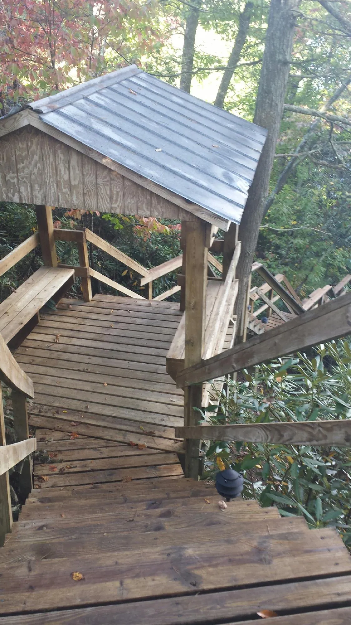 Metal roofed shelter over wooden steps on a wooded walkway — Skylight Repair & Installation work by our crew in Admire