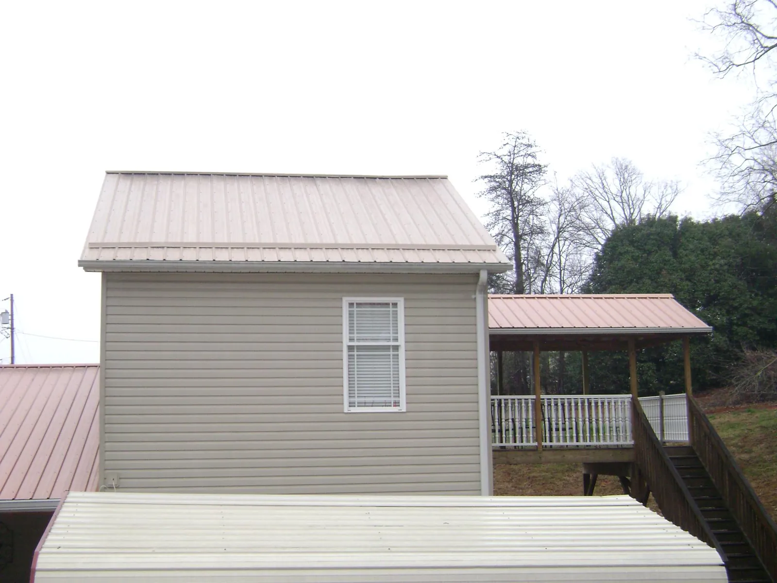 Tan metal roofs on a two story addition and attached porch, from a Roof Replacement job in Admire